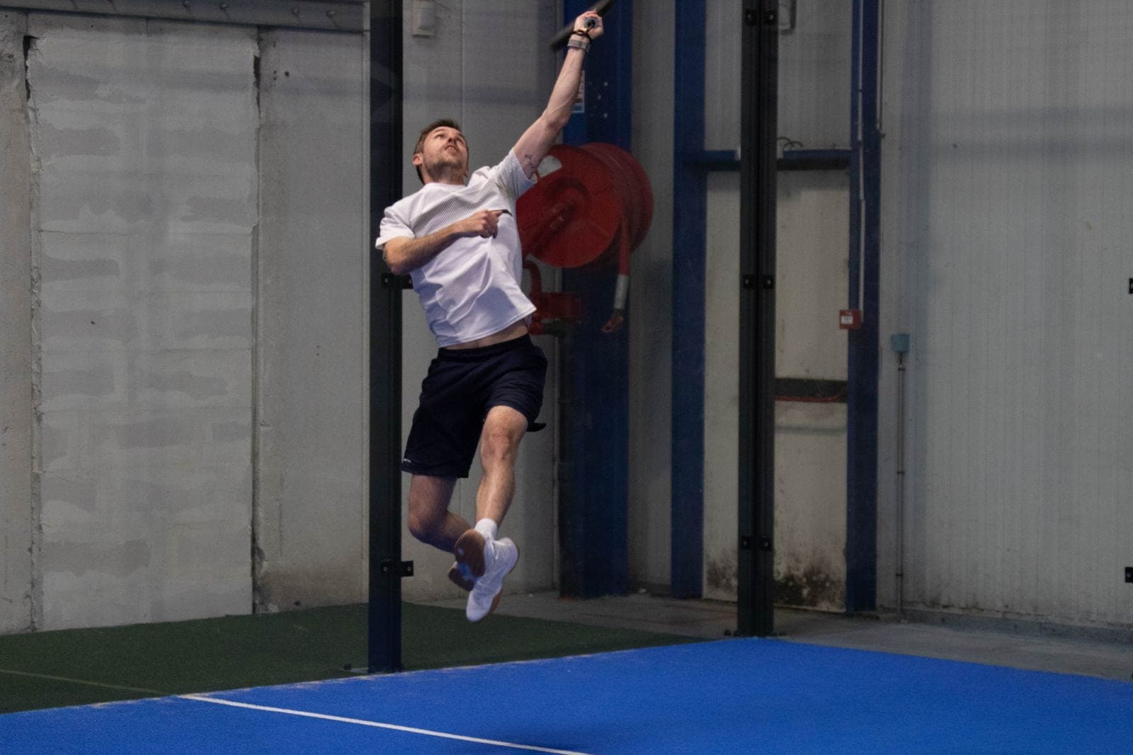 Joueur en pleine détente pour reprendre une balle haute sur un terrain bleu, lors du tournoi interne 2026
