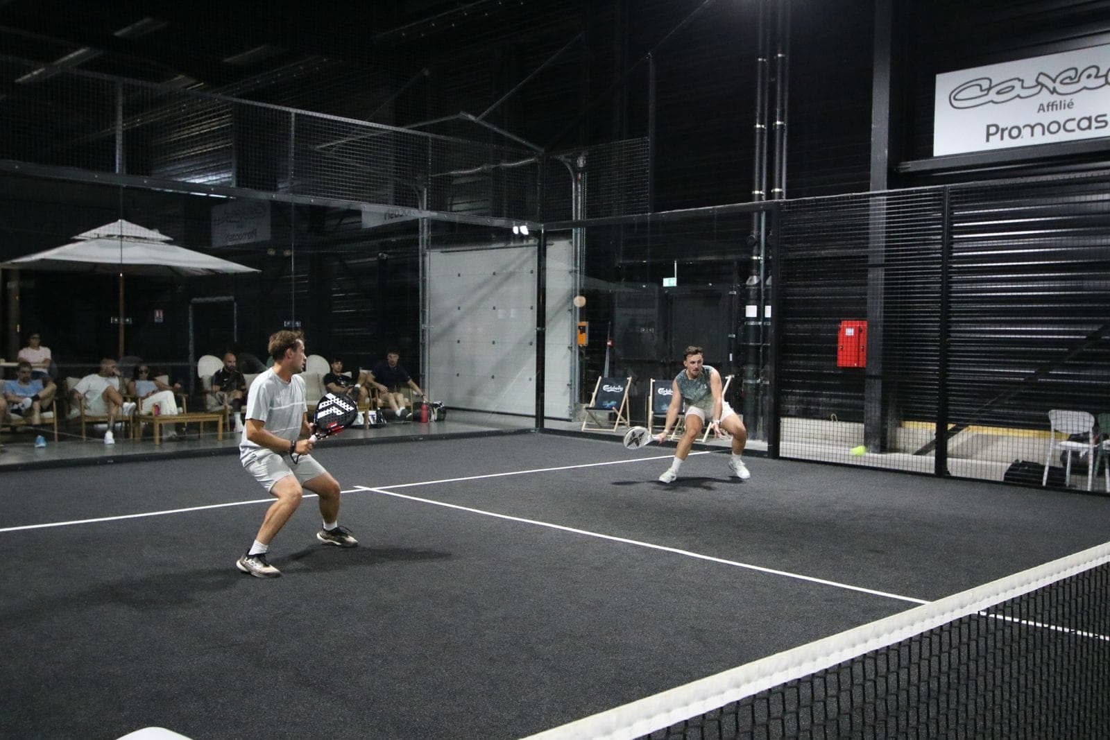 Match de padel sur un terrain noir de l’Arena Complexe